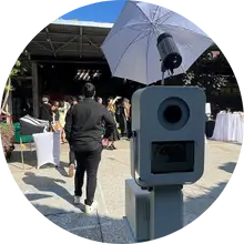 Modern digital photo booth setup with umbrella light, staffed by a pro attendant at an outdoor event by beUtiful Pixels