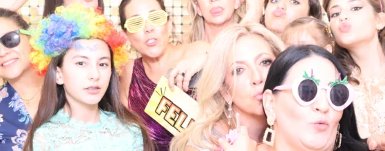 Group of guests posing with fun props in a beÜtiful Pixels photo booth at an event.