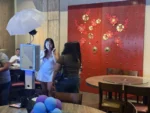 Guest standing near a self-serve digital photo booth inside an event venue.