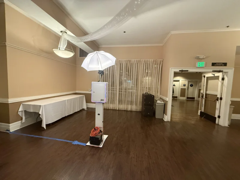 Self-serve digital photo booth set up in an open event room with draped ceiling decor.