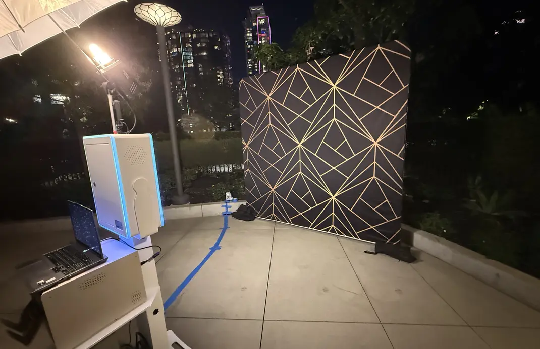 Photo booth facing a black and gold geometric backdrop at an outdoor nighttime event, creating a clean and polished photo area.