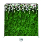 Green wall photo booth backdrop with lush foliage and white blush floral accents across the top.