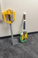 A character-themed video game keyblade and a green toy guitar leaning against a wall for a fun kids birthday photo booth.