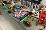 A deluxe photo booth prop table with a Santa hat teddy bear, "It's Lit" signs, gold chains, and money bags ready for a corporate holiday party.